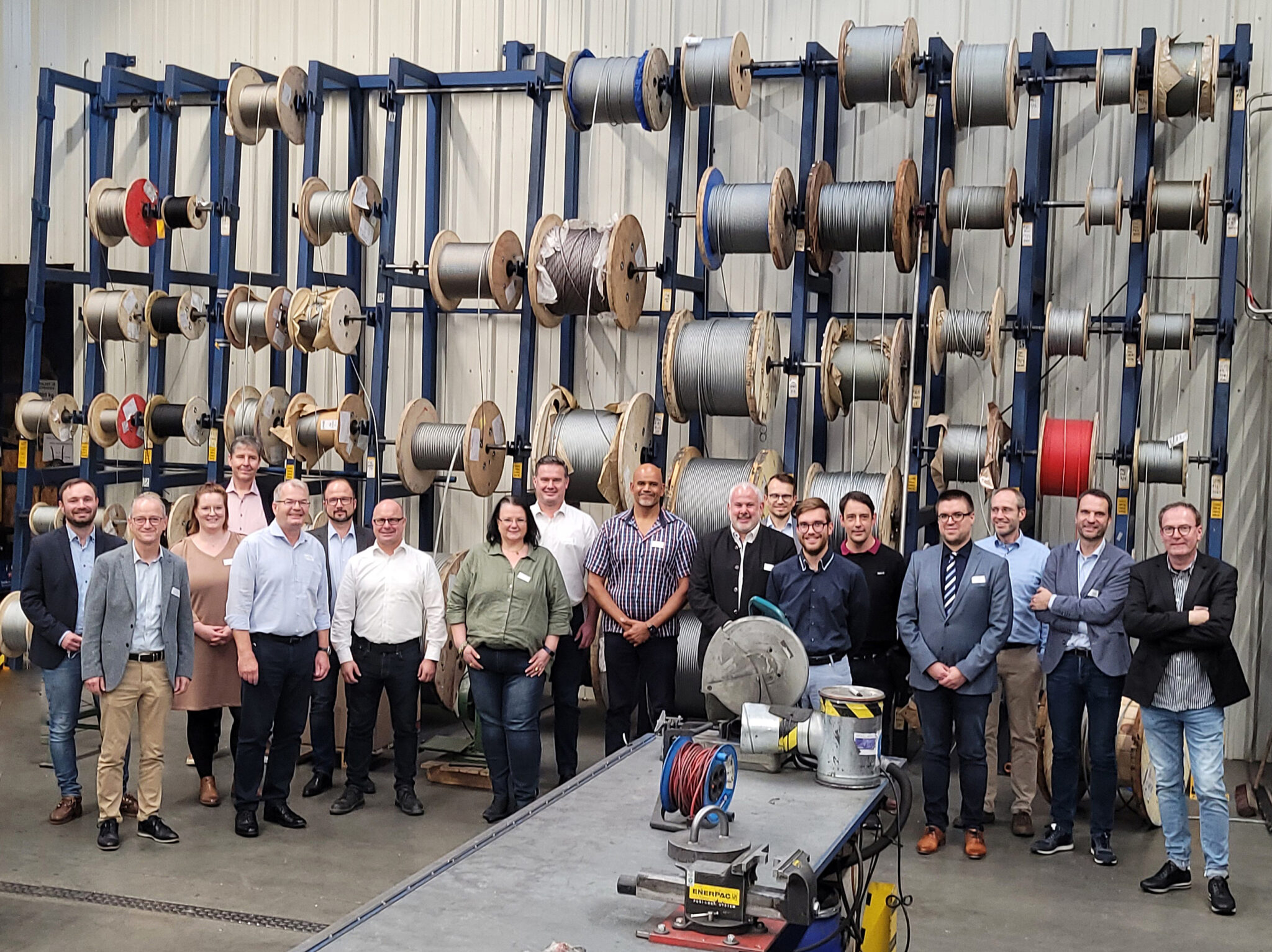 Mitglieder des Technologie-Transfer-Zentrums (TTZ) Kitzingen zu Besuch bei Wiedenmann Seile. Gruppenfoto vor einer beeindruckenden Seil-Lagerwand in der Produktion.
