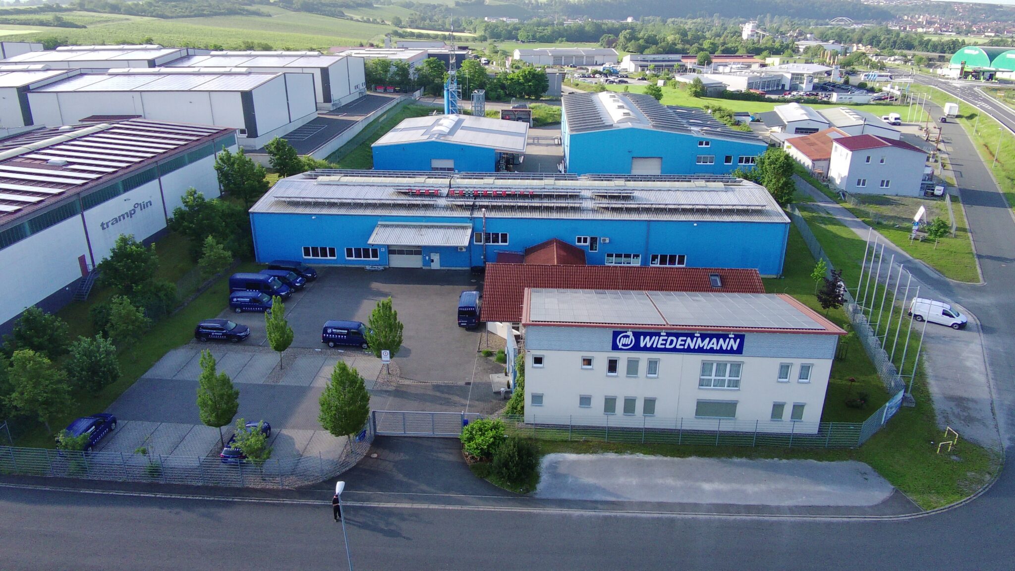 Luftaufnahme des Firmenhauptsitzes von Wiedenmann-Seile GmbH mit blauen Lagerhallen und Verwaltungsgebäude.